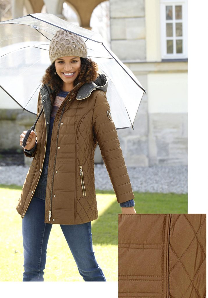 Frau im Herbst Outfit mit Steppjacke, Jeans, Mütze und Regenschirm