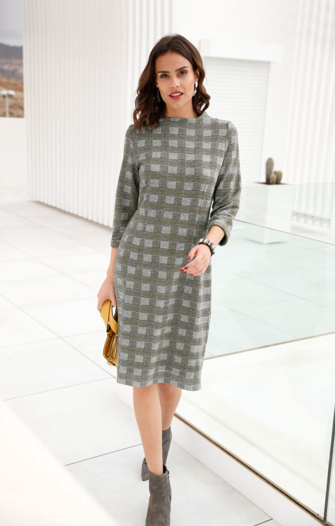Frau mit Glencheck-Kleid in Grau, grauen Stiefeletten und Handtasche